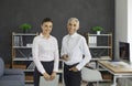 Senior male boss and young female secretary standing in office portrait Royalty Free Stock Photo