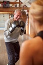 Senior Male Boxer Sparring With Younger Female Coach In Gym Using Training Gloves Royalty Free Stock Photo