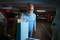 Senior male buyer loading colorful shopper bags into car trunk