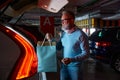 Senior male buyer loading shopper bags into car trunk