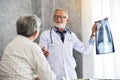 Male doctor and Asian patient are examining x-ray film together. Royalty Free Stock Photo