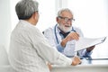 Senior male Doctor is discussing with Asian male patient. Royalty Free Stock Photo