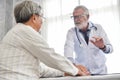 Senior male Doctor is discussing with Asian male patient. Royalty Free Stock Photo