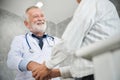 Senior male Doctor is handshaking to Asian male patient. Royalty Free Stock Photo