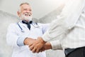 Senior male Doctor is handshaking to Asian male patient. Royalty Free Stock Photo