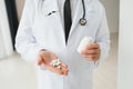 Senior male doctor with stethoscope in medical scrubs and holding bottle and tablets Royalty Free Stock Photo