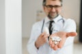 Senior male doctor with stethoscope in medical scrubs and holding bottle and tablets Royalty Free Stock Photo