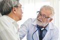 Senior male Doctor is talking with Asian male patient. Royalty Free Stock Photo