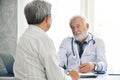 Senior male Doctor is talking with Asian male patient. Royalty Free Stock Photo