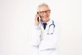 Senior male doctor using mobile phone while standing at isolated white background Royalty Free Stock Photo