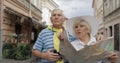 Senior male and female tourists standing with a map in hands looking for route Royalty Free Stock Photo