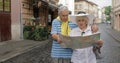 Senior male and female tourists standing with a map in hands looking for route Royalty Free Stock Photo