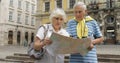 Senior male and female tourists standing with a map in hands looking for route Royalty Free Stock Photo