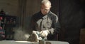 Senior male master working at wood factory grinding with headsaw the wooden board.