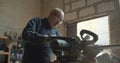 Senior male master works at wood factory pressing the headsaw cutting the wood.