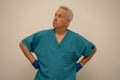 Senior male nurse with hands on hips glancing upward away from camera Royalty Free Stock Photo