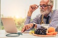 Senior male nutritionist doctor working on laptop.