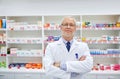 Senior male pharmacist in white coat at drugstore