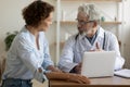 Senior male professional physician consulting female patient using laptop Royalty Free Stock Photo