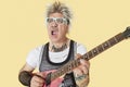 Senior male punk musician playing guitar over yellow background Royalty Free Stock Photo