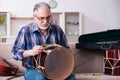 Senior male repairman repairing musical instruments at home Royalty Free Stock Photo