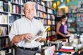 Senior male shopper is choosing book for reading