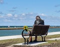 Senior male sits on bench overlooking Lake Ontario, Canada