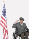 Senior male US military officer saluting American flag over gray background Royalty Free Stock Photo