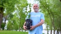 Senior male volunteer holding plant seedling smiling camera, reforestation