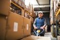 Senior male warehouse worker pulling a pallet truck. Royalty Free Stock Photo