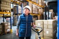 Senior male warehouse worker pulling a pallet truck.