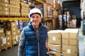 Senior male warehouse worker or a supervisor pulling a pallet truck with boxes. Royalty Free Stock Photo