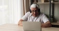 Senior male wear earphones confer online using app on laptop