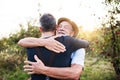 A senior man and adult son standing in apple orchard in autumn, hugging. Royalty Free Stock Photo