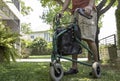 A senior man as he strolls with his wheeling walker in garden