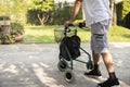 Senior man as he strolls with his wheeling walker in garden