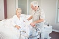 Senior man assisting ill woman in getting up from bed Royalty Free Stock Photo