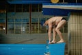 Senior man athlete standing on starting block preparing to jump in pool