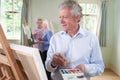 Senior Man Attending Painting Class With Teacher In Background Royalty Free Stock Photo
