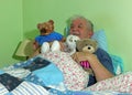 Senior man in bed with soft cuddly toys.