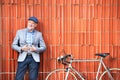 Senior man with bicycle standing against brick wall.