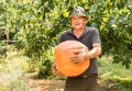 Senior man with big organic orange pumpkin harvested in the vegetable garden Royalty Free Stock Photo