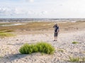 Senior man with binoculars looking at dried out boat on tidal flats at low tide of Waddensea from beach of Boschplaat on