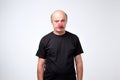 Senior man in black tshirt standing with red clown nose in depression.