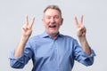 Senior man in blue shirt showing victory sign