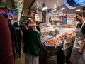 Senior man in boater and green jacket looks over fish counter, P