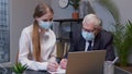 Senior man boss with woman secretary in medical mask working in office during coronavirus pandemic Royalty Free Stock Photo