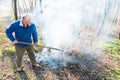 Senior man is burning dry branches. Royalty Free Stock Photo