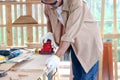 Senior man carpenter working in carpentry woodwork workshop, old craftsman  working withelectric grinder on wood and enjoy his DIY Royalty Free Stock Photo