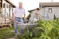 Senior man carrying garden tools in a wheelbarrow Royalty Free Stock Photo